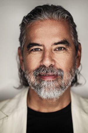 Portrait of Henk Rogers wearing a white suite jacket and black tshirt underneath.